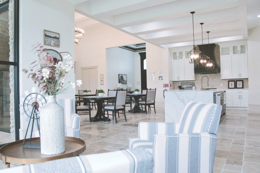 Common area at Needville Cottage with striped armchairs, opening onto the dining room and kitchen